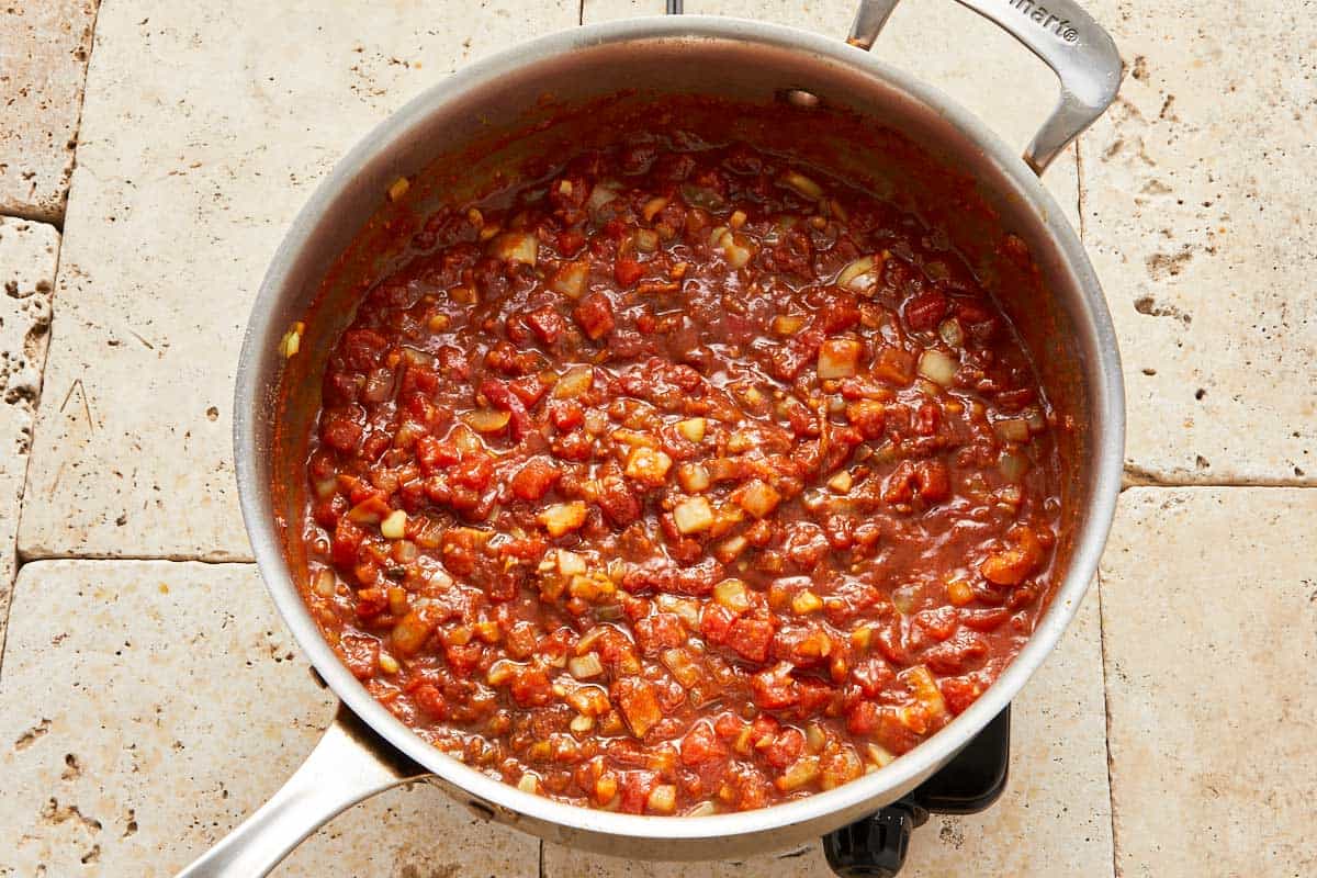 Preparation of the sauce with spices, butter, and onions being sautéed in a skillet.