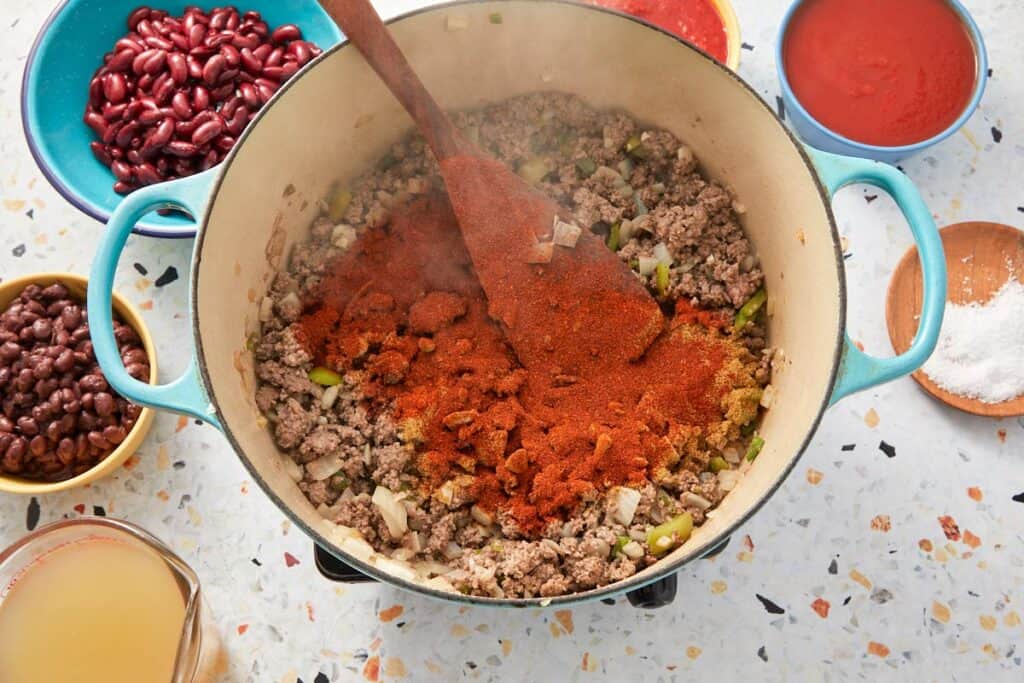 Adding seasoning to the pan with beef