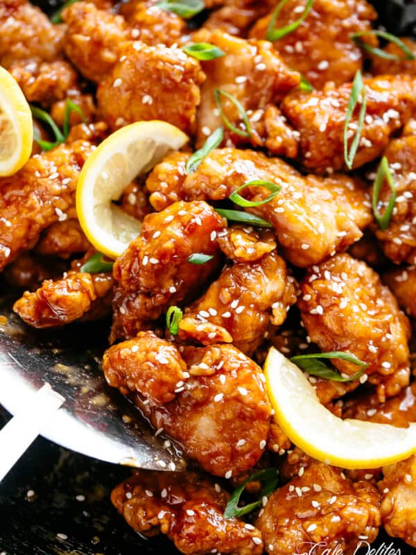 Chicken bites with a sticky, sweet and sour, Chinese lemon sauce, sprinkled with sesame seeds and sliced spring onion in a pan