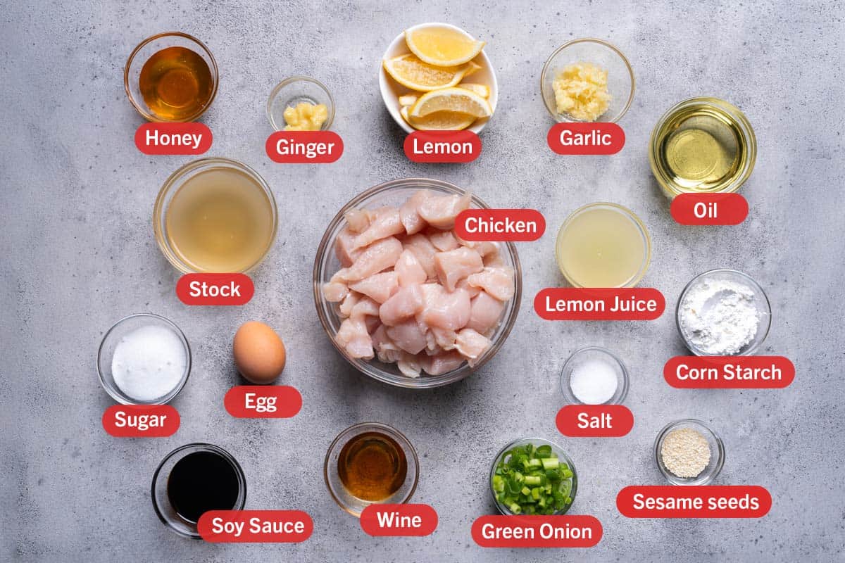 Ingredients laid out with honey, ginger, lemon, garlic, oil, stock, chicken, lemon juice, corn starch, sugar, egg, salt, soy sauce, wine, green onion, sesame seeds