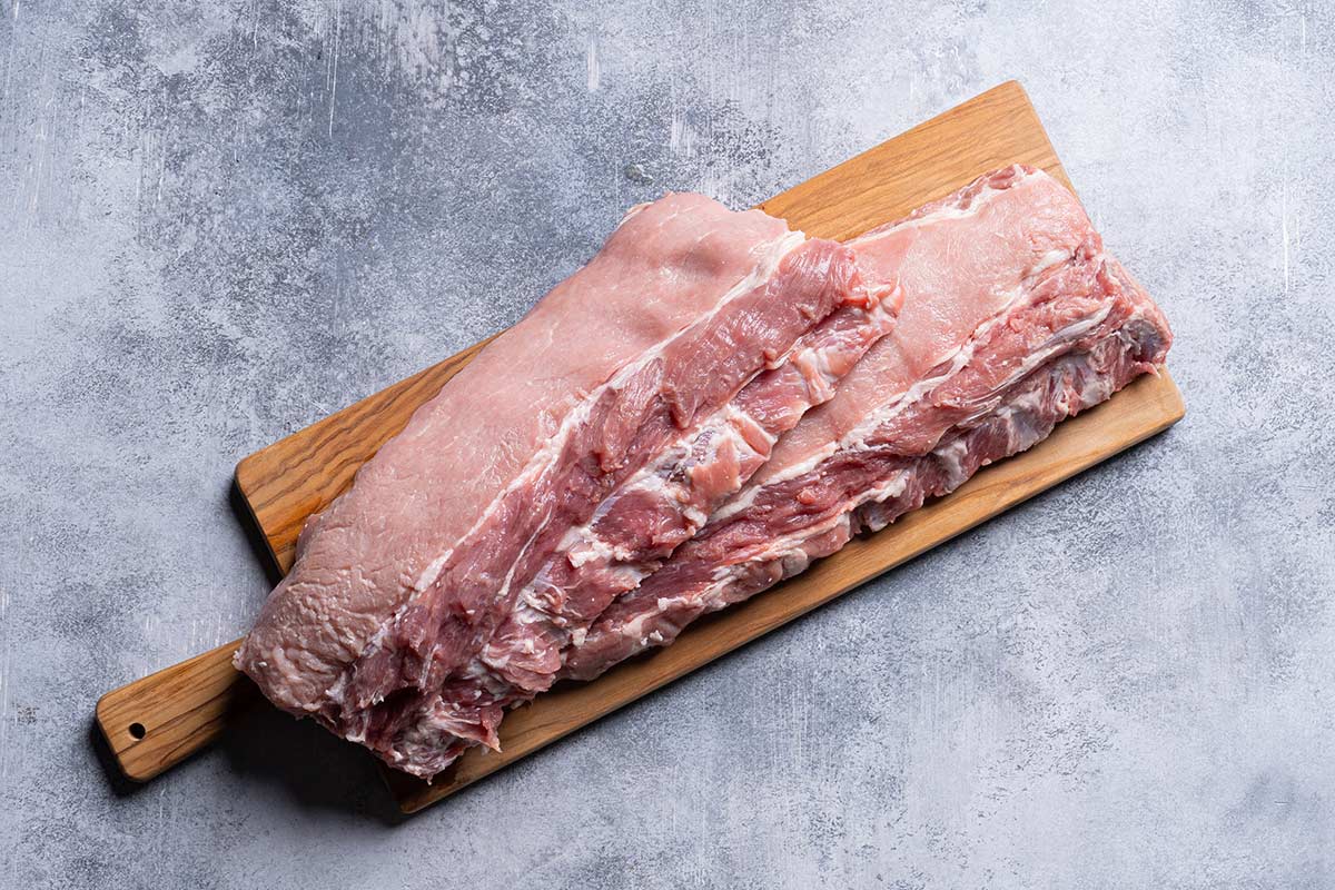 Baby back ribs raw sitting on a wooden cutting board