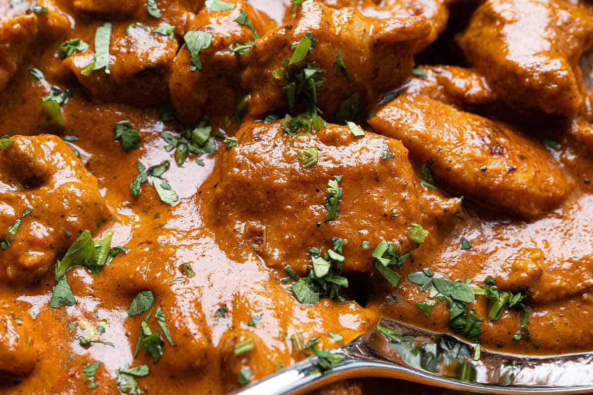 chicken and sauce close up with a fork garnished with cilantro