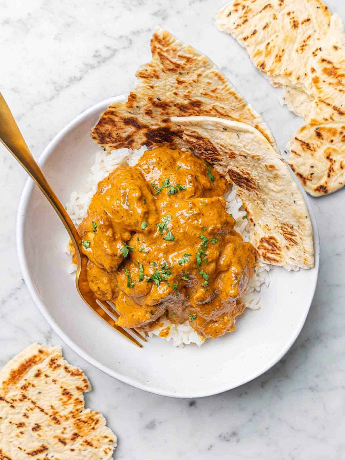 Butter chicken served over rice and naan in a bowl looks yum