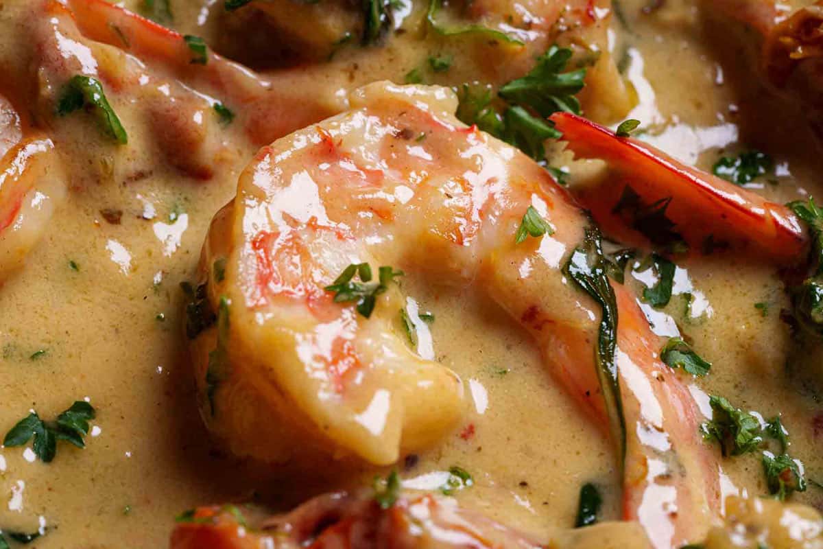 An image of the shrimp being added back to the sauce, with parsley sprinkled on top.