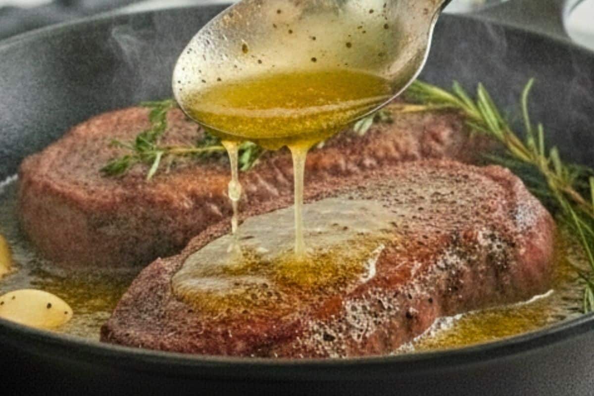 Carefully tilt the pan toward you and use a spoon to baste the steaks with butter.