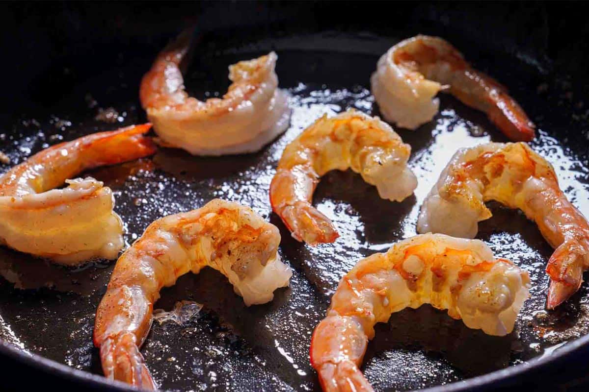 Image of shrimp being cooked over medium heat in a skillet with garlic.