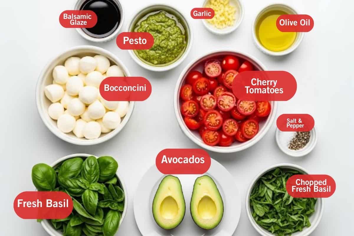 Flat lay photo of ingredient shot of balsamic glaze, pesto, garlic, olive oil, bocconcini, cherry tomatoes, salt and pepper, chopped fresh basil, avocados, fresh basil