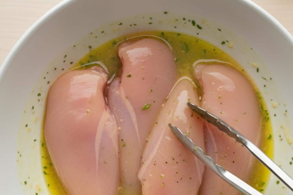 Chicken breasts in a bowl with egg mixture.