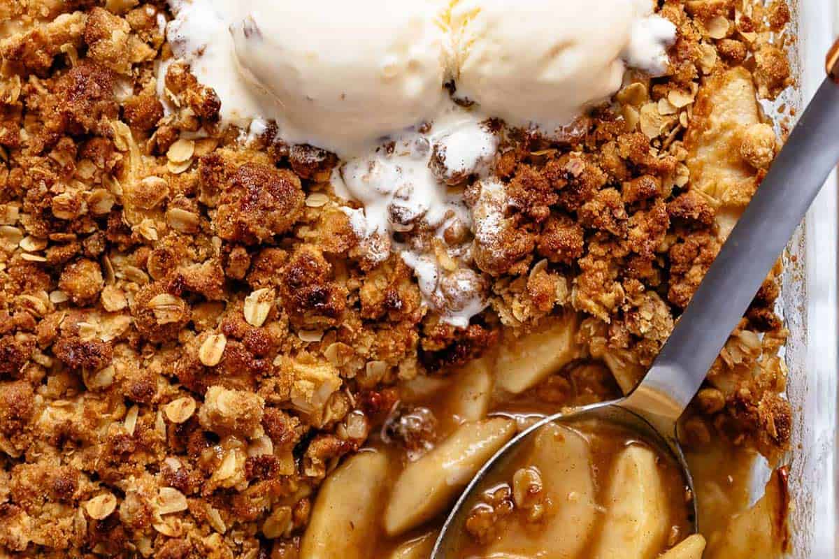 Close-up shot of Apple Crumble topped with vanilla ice cream.