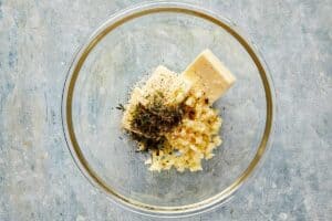 Butter, garlic, thyme, salt, and pepper in a bowl ready to be mixed