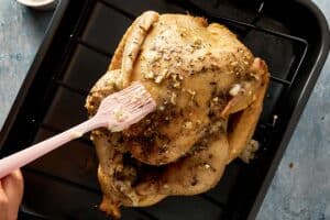 Brushing herb butter over cooked turkey before crisping skin