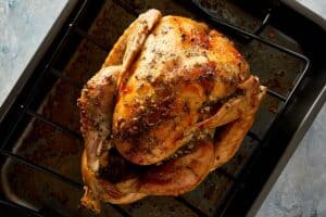 Cooked turkey being transferred carefully to a baking tray