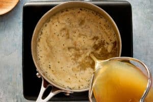 Pouring turkey broth into roux while whisking