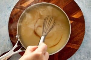 Finishing homemade turkey gravy with Worcestershire sauce while whisking