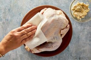 Patting whole turkey dry with paper towels before cooking