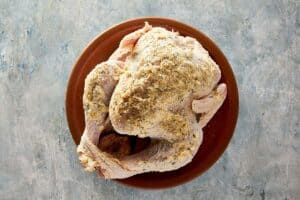 Raw whole turkey coated with herb butter and seasoning