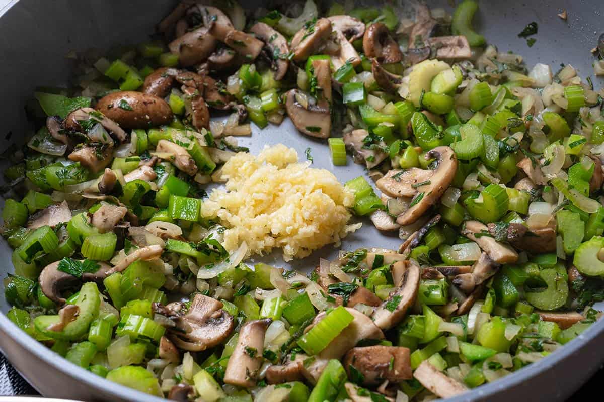 mushrooms, onions, celery, parsley, sage, Green bell pepper, thyme being sauted in a pan