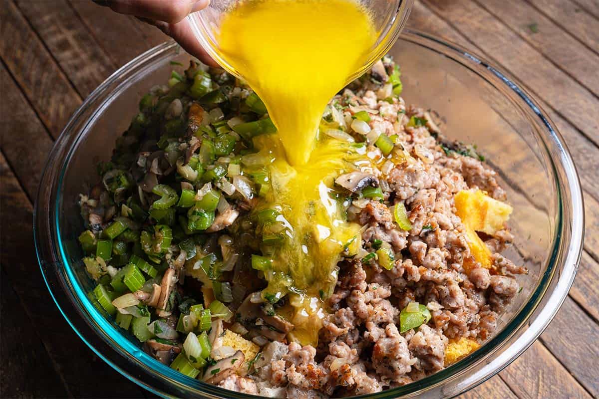 cornbread dressing mixture in a bowl being covered with stock and melted butter