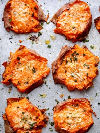 Pieces of Garlic Butter Smashed Sweet Potatoes With Parmesan kept on baking paper