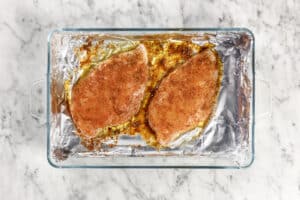 seasoned chicken in a tray with foil