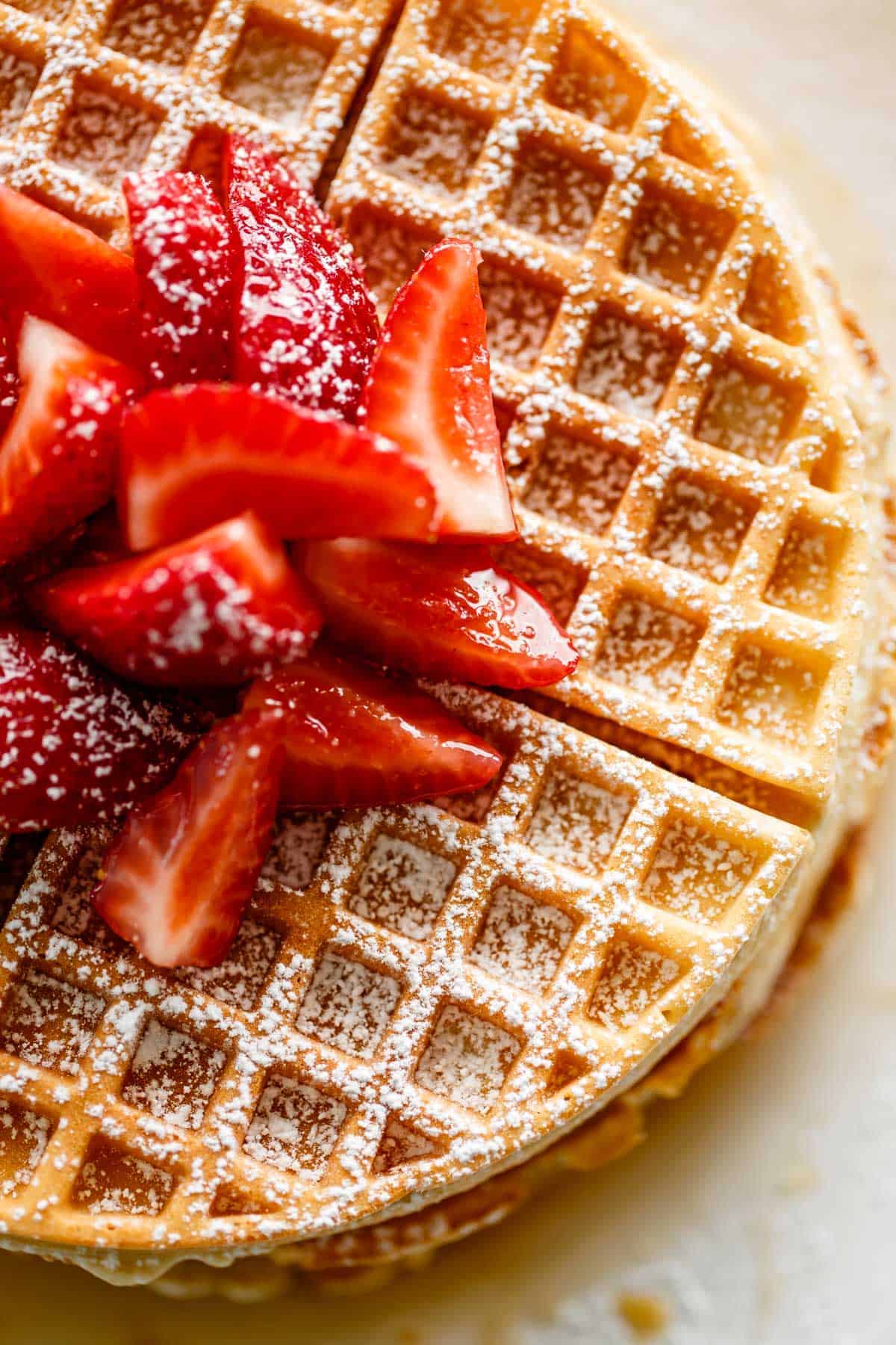 Belgian Waffles with powdered sugar and chopped strawberries.