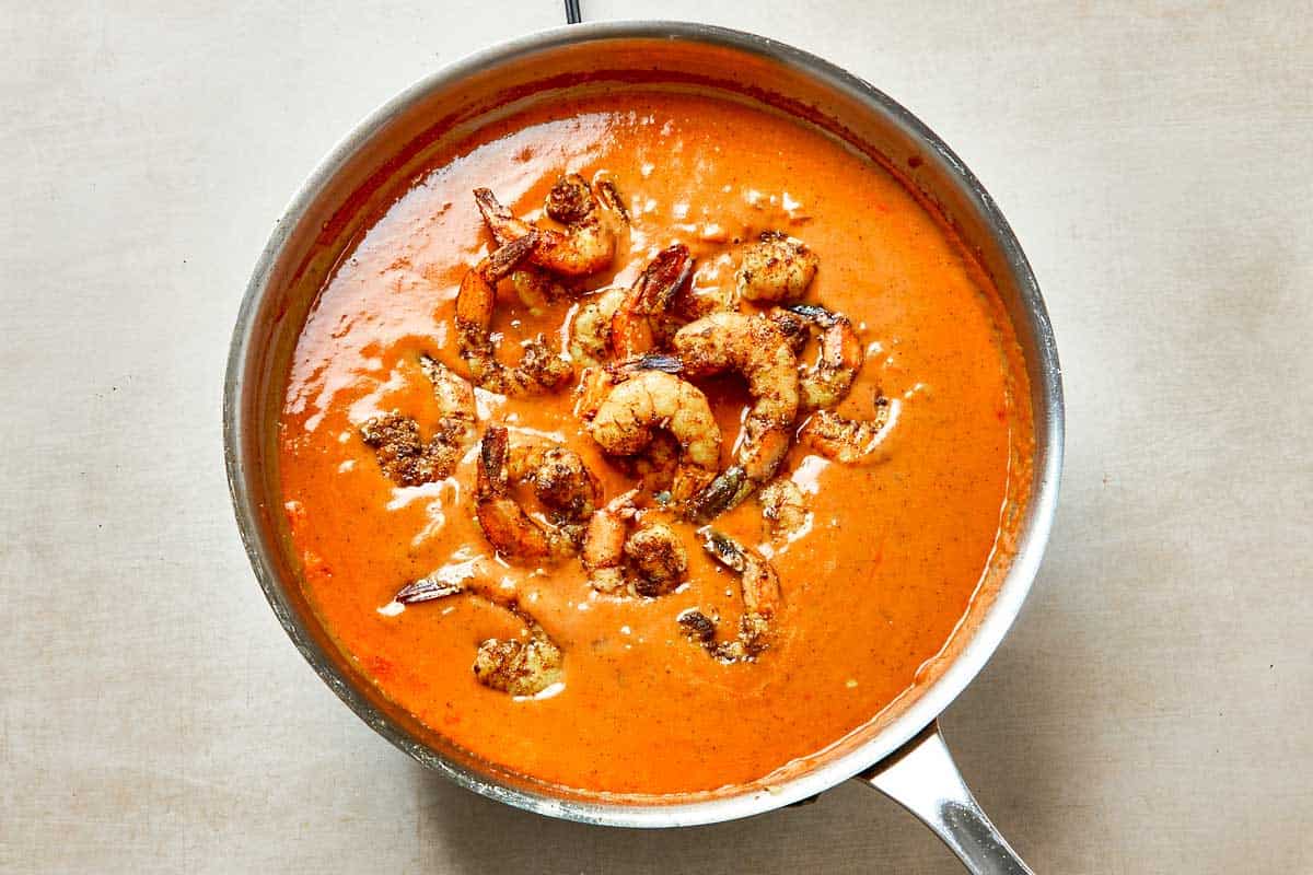 A pan filled with pink, plump shrimp simmering in a rich sauce.