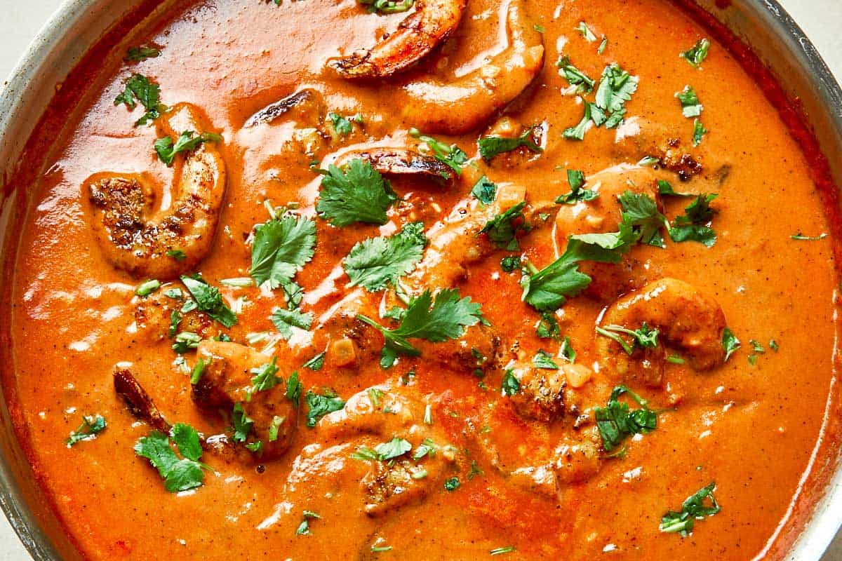A pan filled with pink, plump shrimp simmering in a rich sauce, ready to be served.