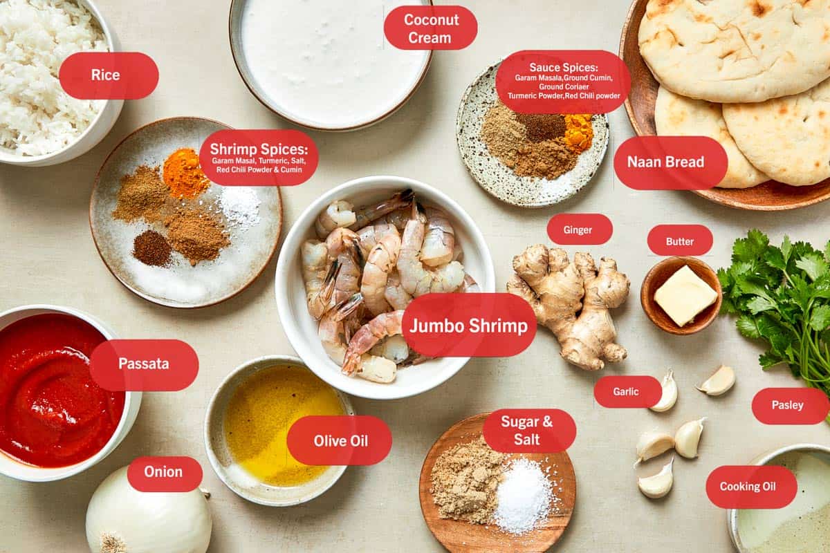 Flatlay image of labeled ingredients for Coconut Shrimp, each in individual ceramic bowls on a dark brown surface.
