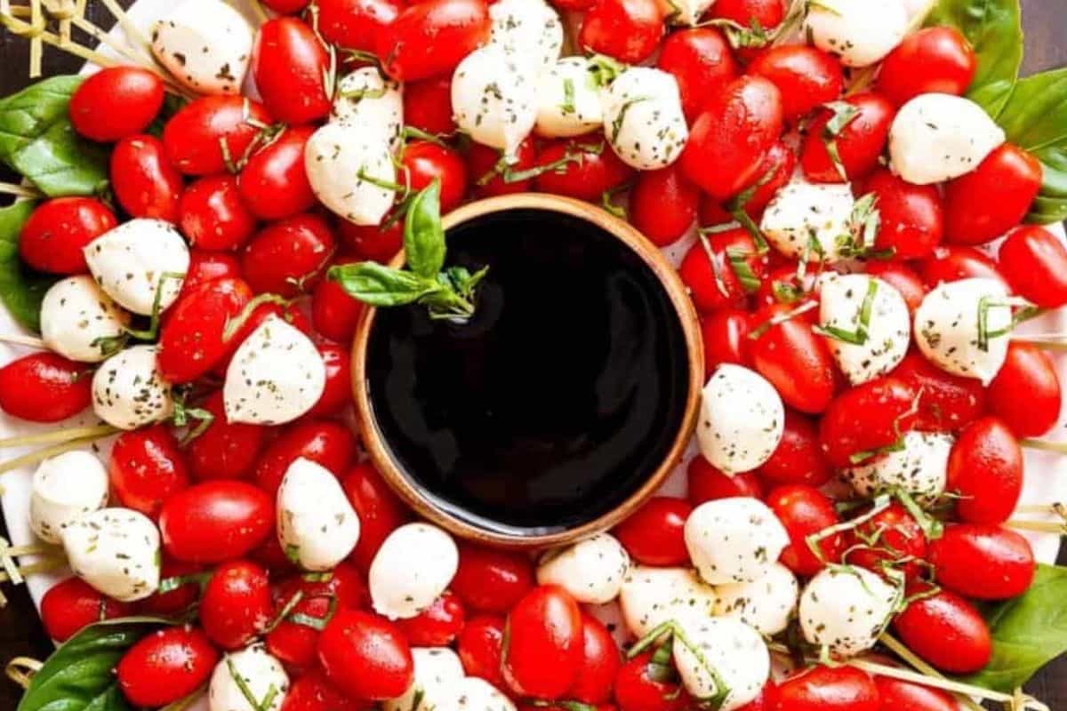Set a small bowl of the balsamic glaze in the center of the platter. Slide toothpicks around and under the tomato and mozzarella balls.