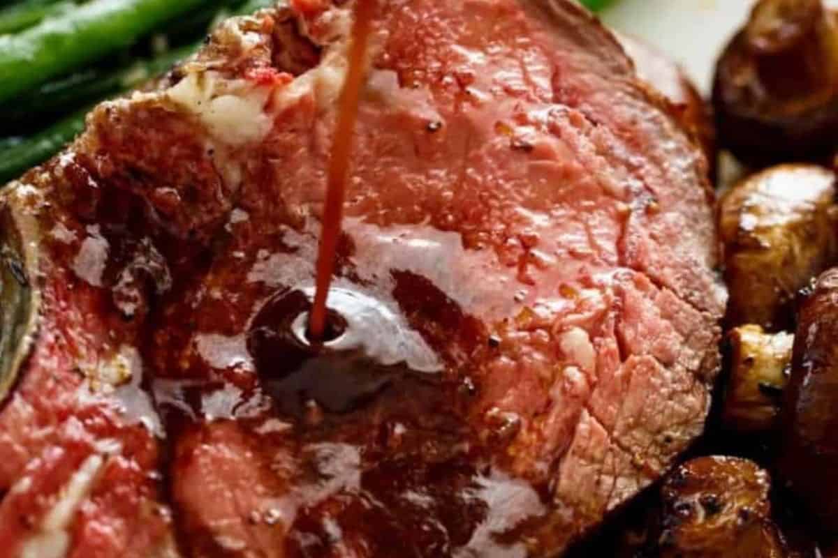 Place the pan with drippings and garlic halves on the stove. Add wine and 2½ cups beef stock, then stir in a cornstarch slurry made with the remaining stock. Simmer until thickened and strain. - 12