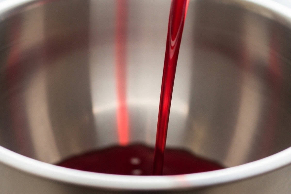 pouring cranberry juice in a steel bowl