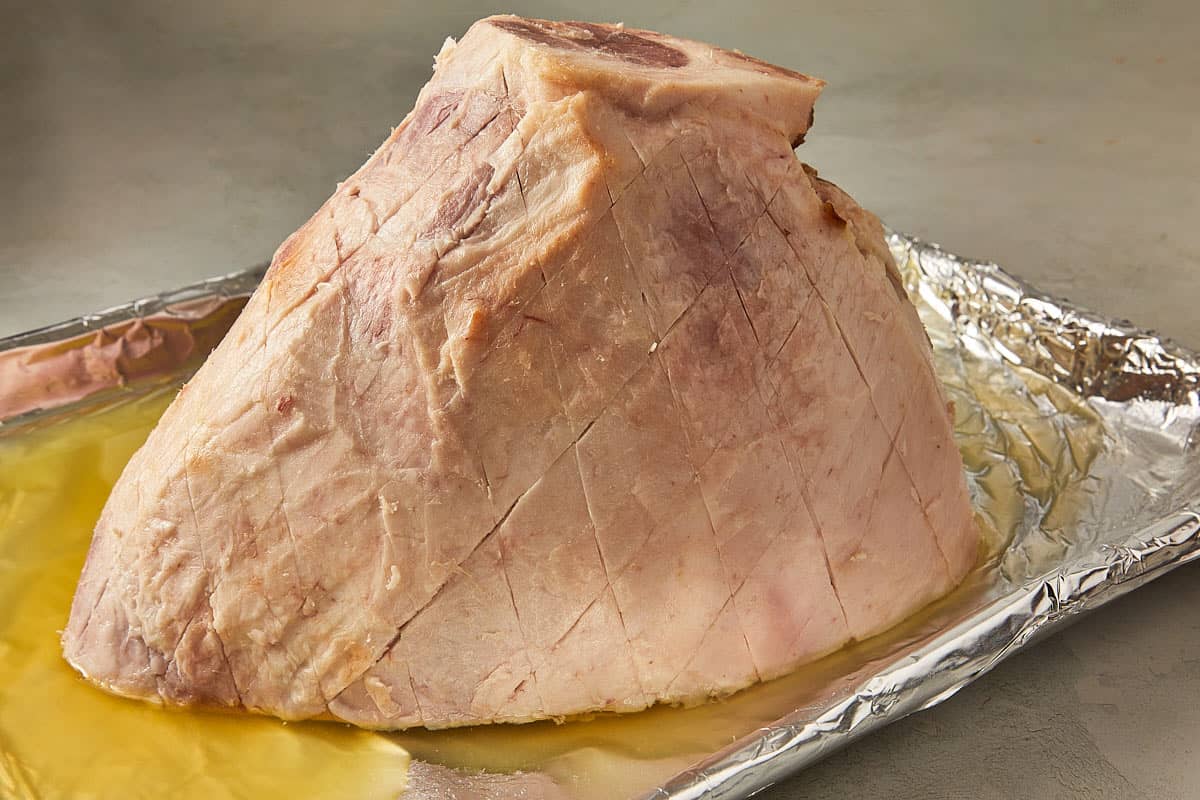 A large piece of ham resting on aluminum foil, showcasing its glistening surface and rich color.