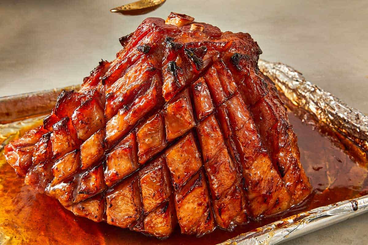 A large maple ham placed on a baking sheet, showcasing its rich color and texture.