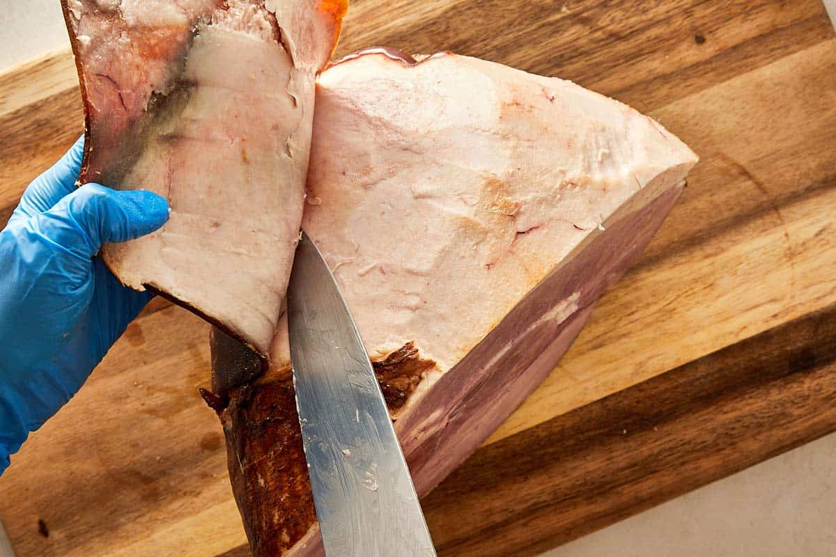 Removing the rind from ham using a knife