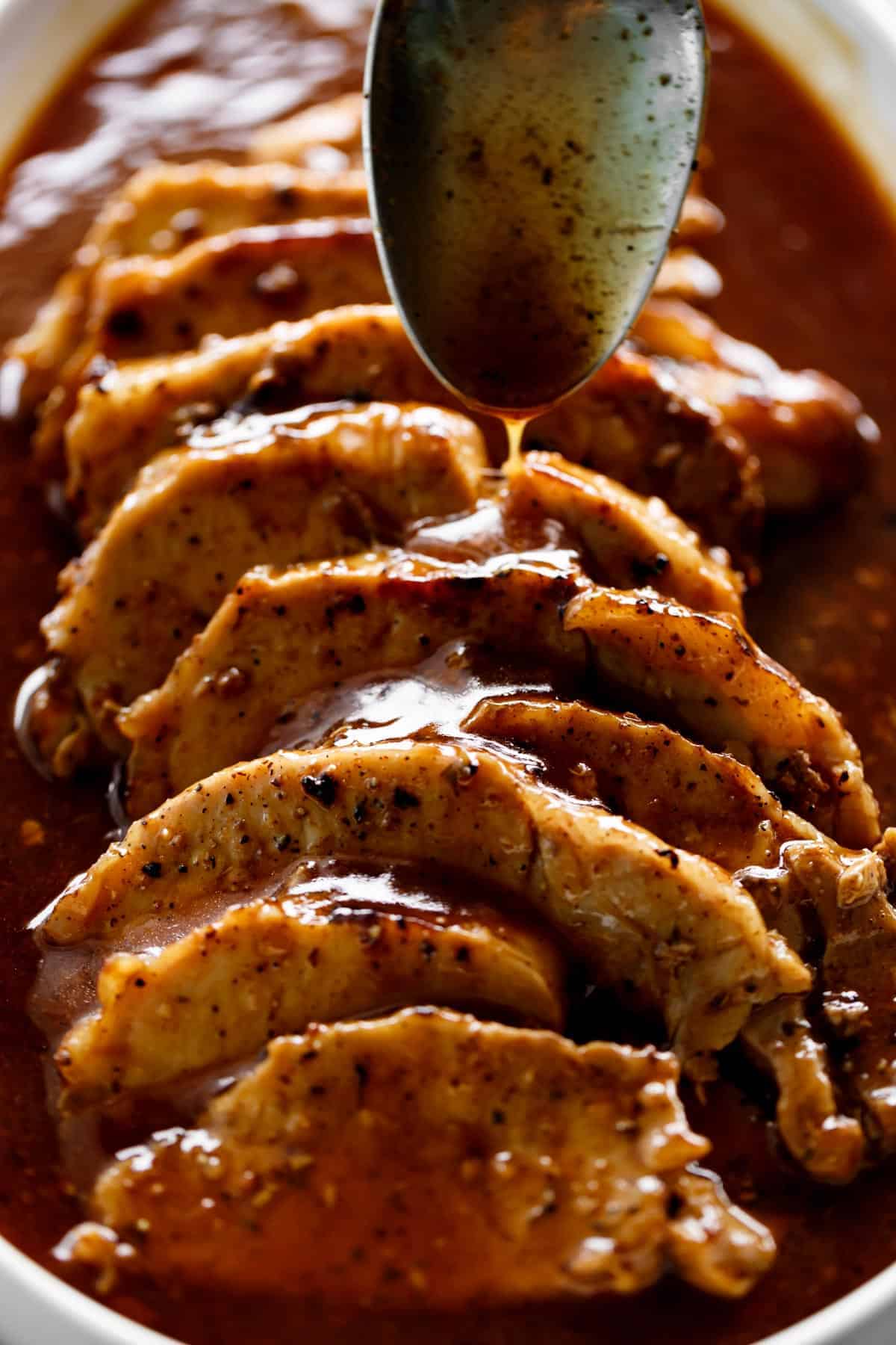 Pork Loin Roast drizzled with a Honey Garlic Butter Sauce on a metal spoon