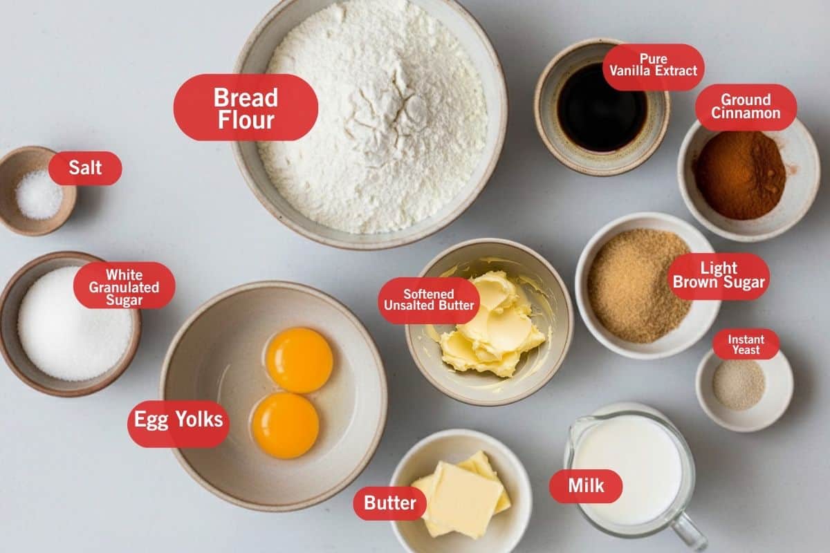 Flat lay photo of ingredient shot of salt, bread flour, white granulated sugar, egg yolks, softened unsalted butter, butter, milk, light brown sugar, instant yeast, ground cinnamon, pure vanilla extract