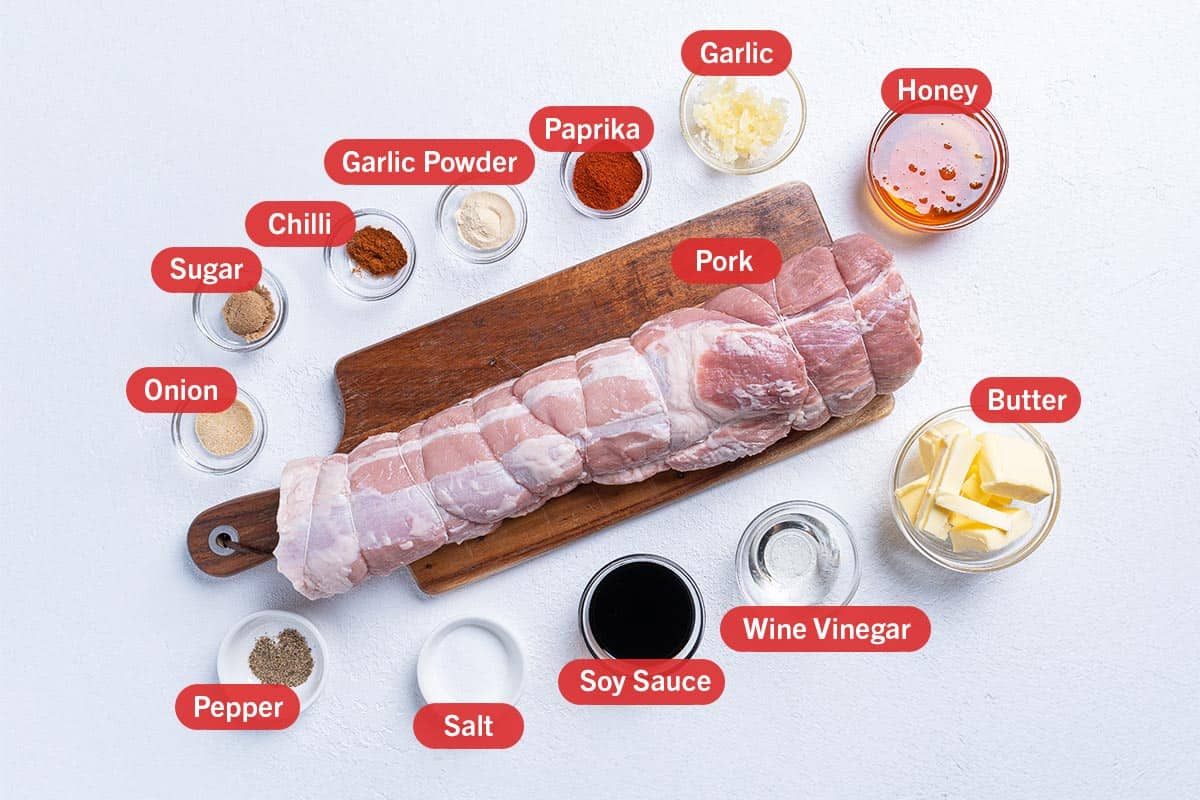 Image of the ingredients needed for the preparation of the Roast Pork Loin, specifically: onion, sugar, chili, garlic powder, paprika, garlic, honey, butter, wine vinegar, soy sauce, salt, pepper, and pork