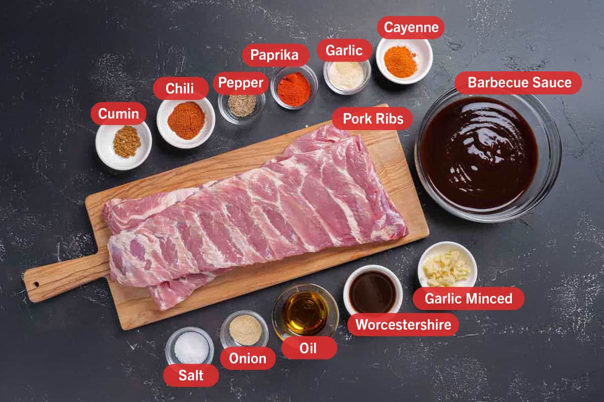 Image of the ingredients needed for the preparation of the Barbecue Ribs, specifically: cumin, chilli, pepper, paprika, garlic, cayenne, barbeque sauce, pork ribs, salt, onion, oil, worcestershire, garlic minced.