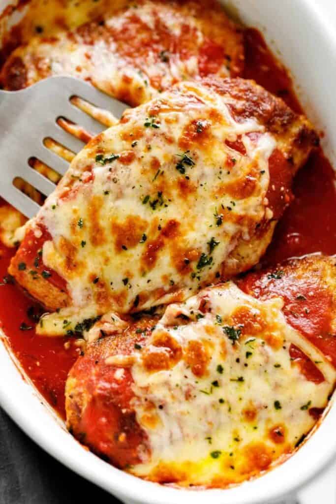 Low carb chicken parmesan covered in marinara sauce and mozzarella cheese in a white plate. 