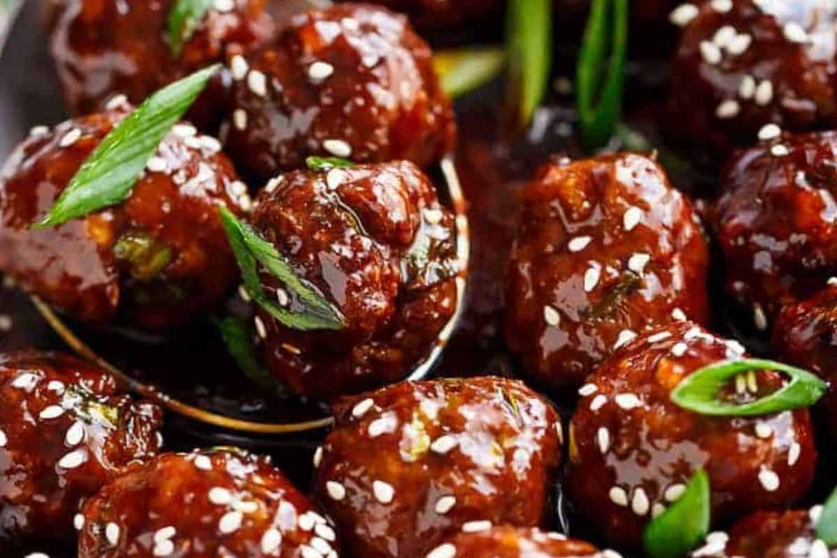 Add half the meatballs to the pan and coat. Garnish with sesame seeds and green onions.