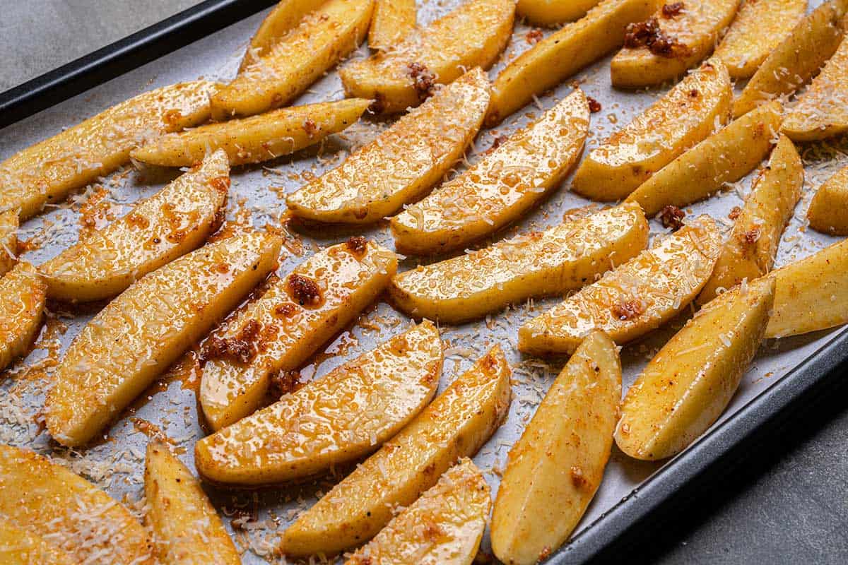 Wedges in a single layer, skin-sides-down, on the baking trays being sprinkled with the seasoning.