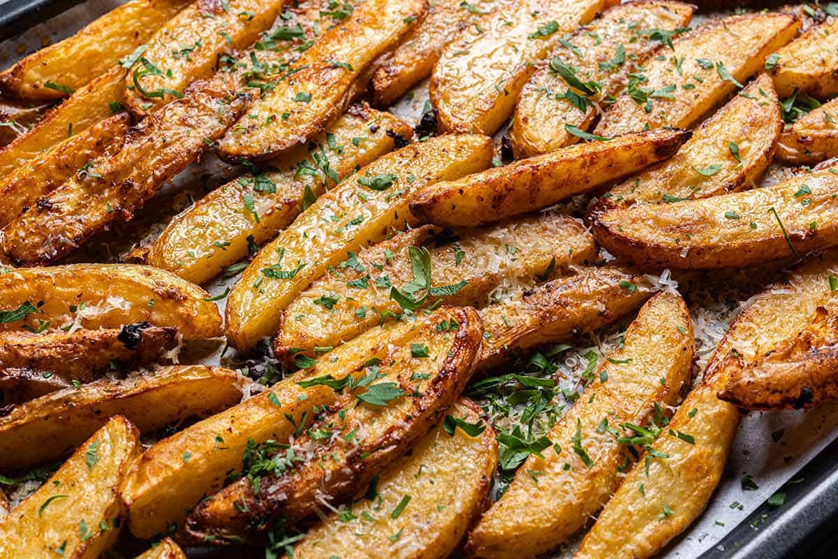 Beautiful golden-brown, crispy potatoes just removed from the oven covered in garlicky sauce and parsley.