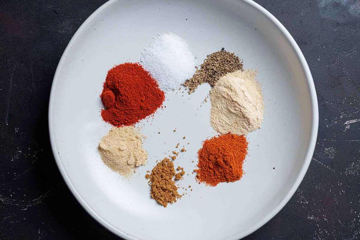 Image showing individual spices for seasoning arranged in a circular pattern on a white round plate.