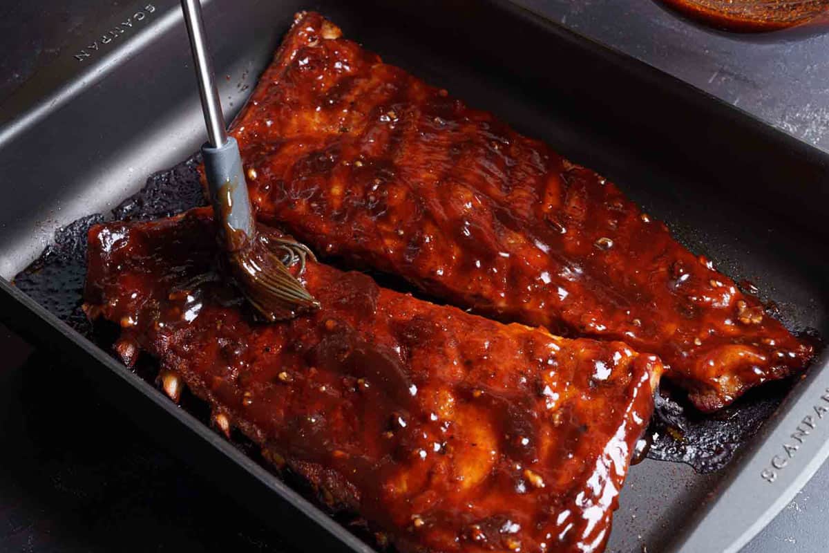 Image of the ribs being brushed with a barbecue sauce mixture.