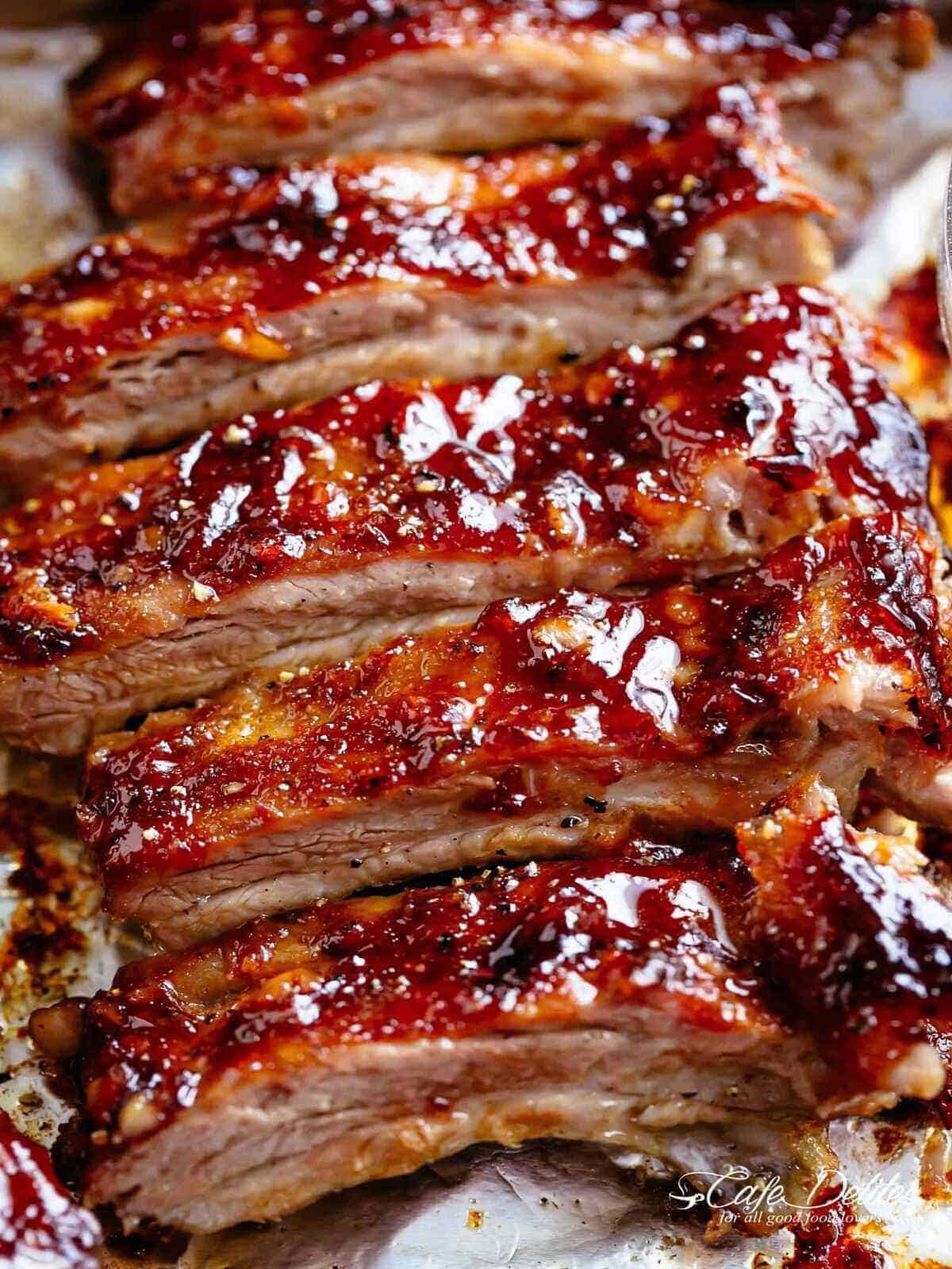 Close-up image of juicy barbecue ribs, dripping in sauce, freshly removed from the oven.