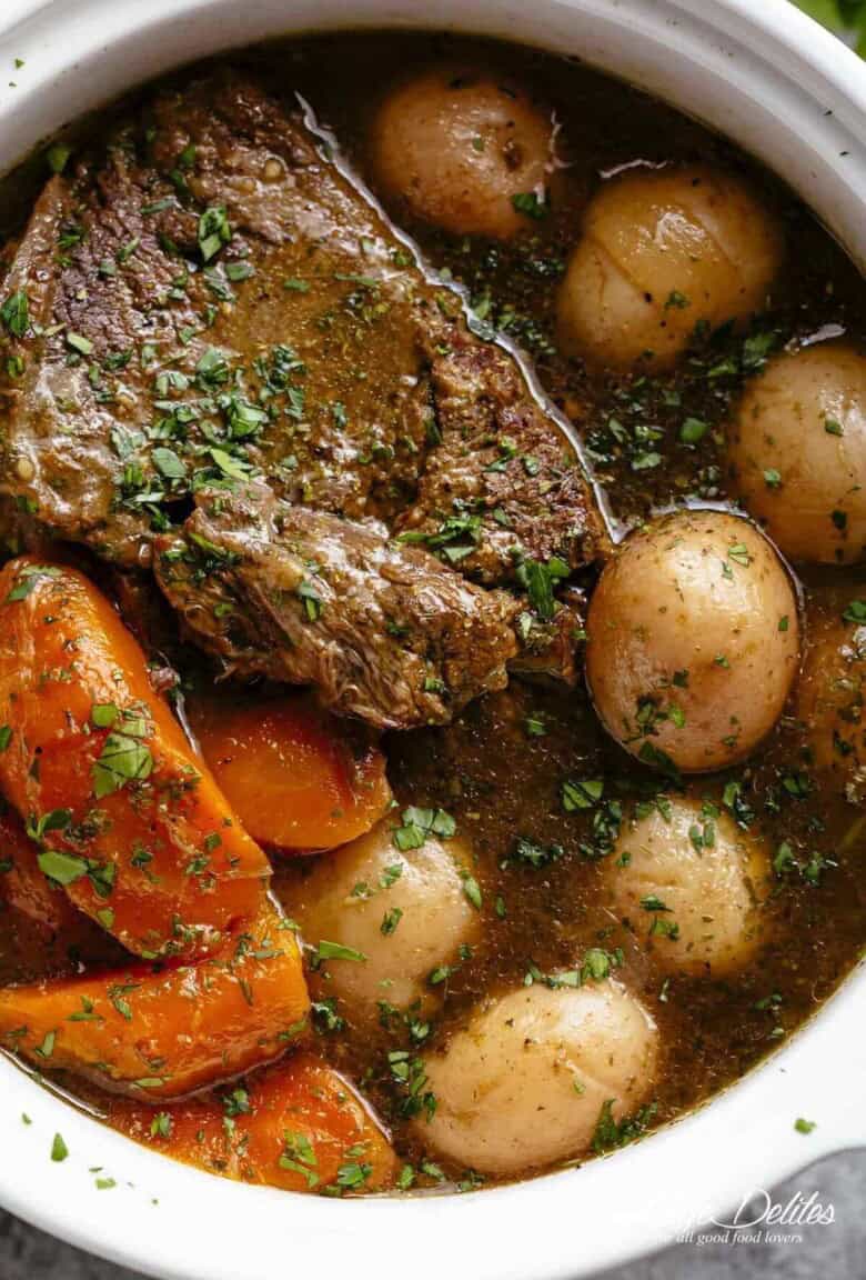 A close-up image of a tender piece of beef chuck, cooked in its own juices alongside potatoes and carrots.