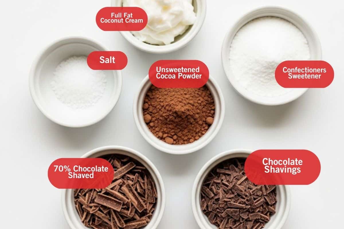 Flat lay photo of ingredient shot of full fat coconut cream, salt, unsweetened cocoa powder, confectioners sweetener, 70% chocolate shaved, chocolate shavings
