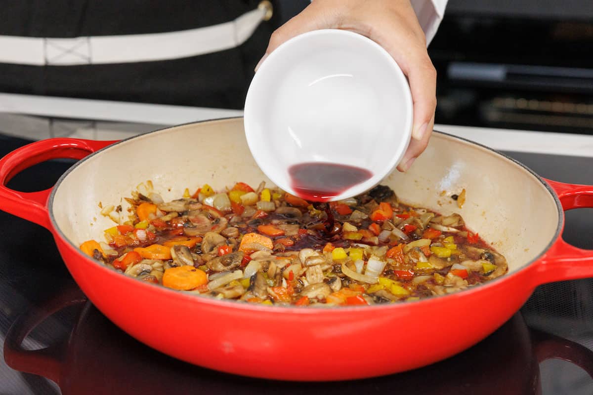 wine being poured into pan with vegetables