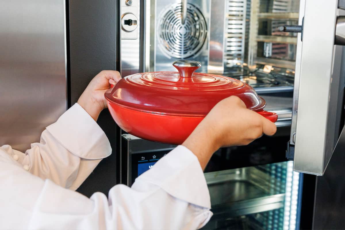 red skillet with lid on being put into oven