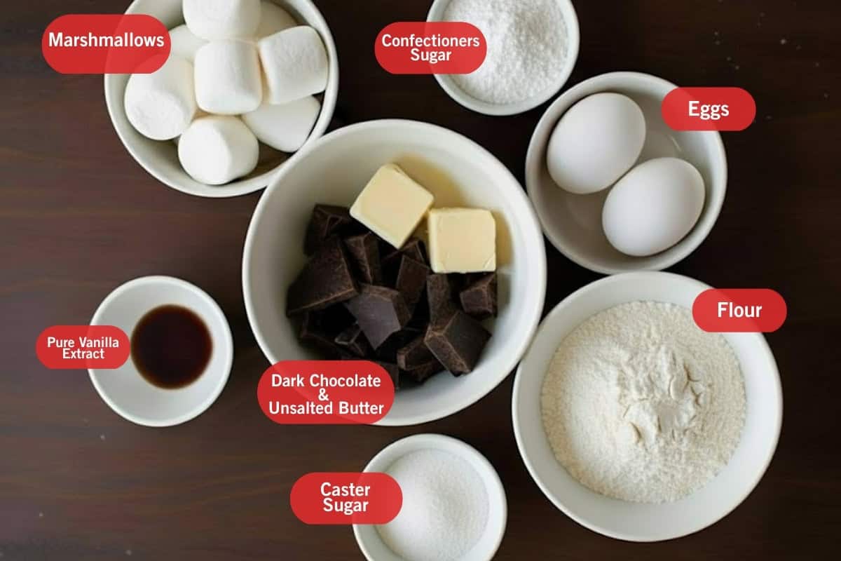 Flat lay photo of ingredient shot of marshmallows, confectioners sugar, eggs, dark chocolate and unsalted butter, pure vanilla extract, caster sugar, flour